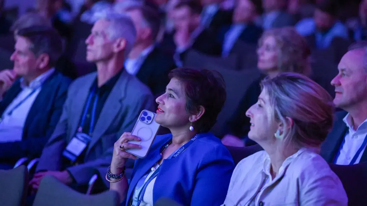 A crowd listens to a speech at a tech conference event.
