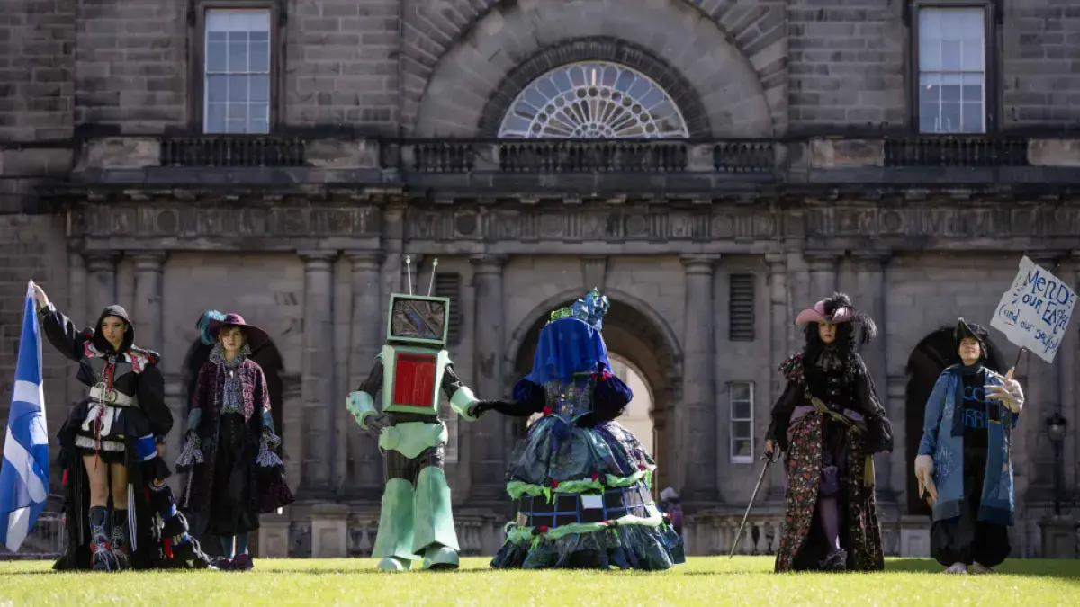 Six student pose in costumes on the Old College Quad lawn during a photocall for the Performance Costume Show 2025