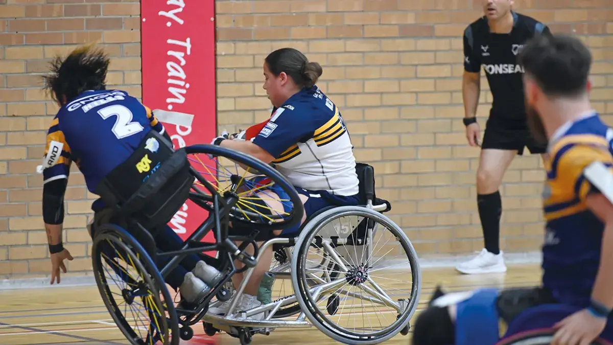 Wheelchair basketball players in the Edinburgh Giants team practice in a University gym facility.