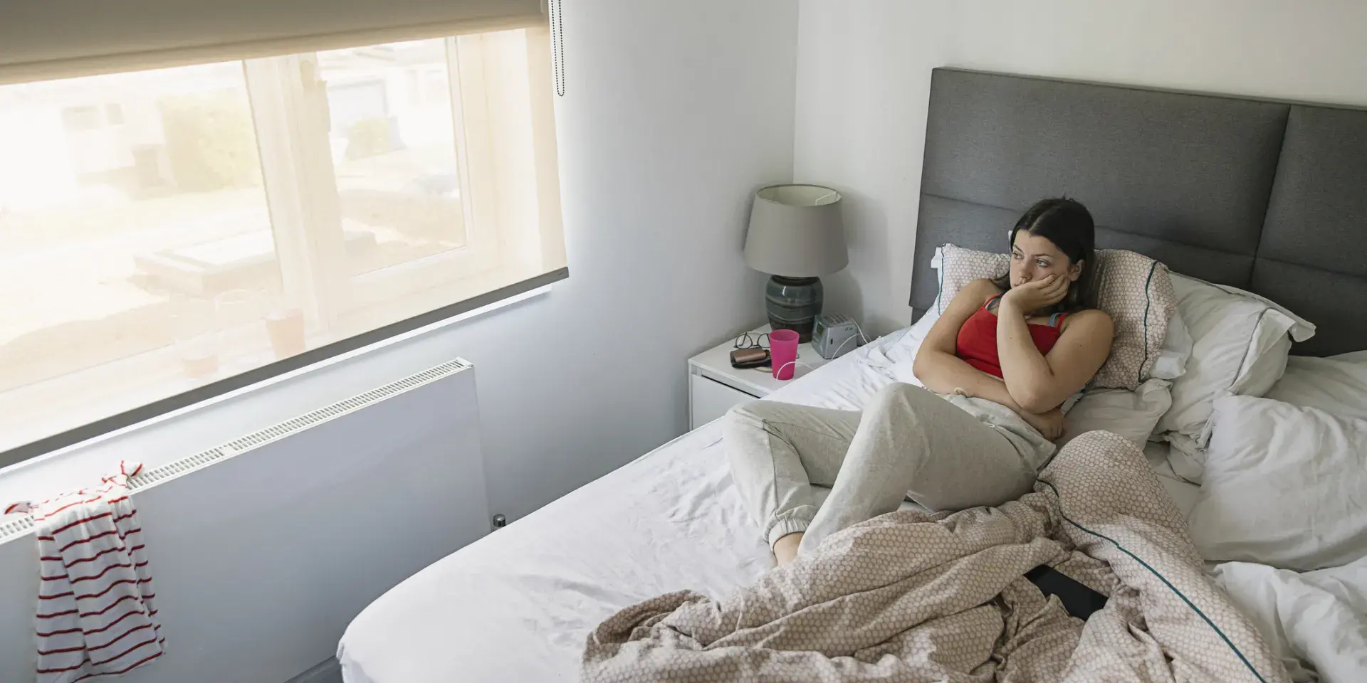 A teenage girl lies in bed looking out of the window