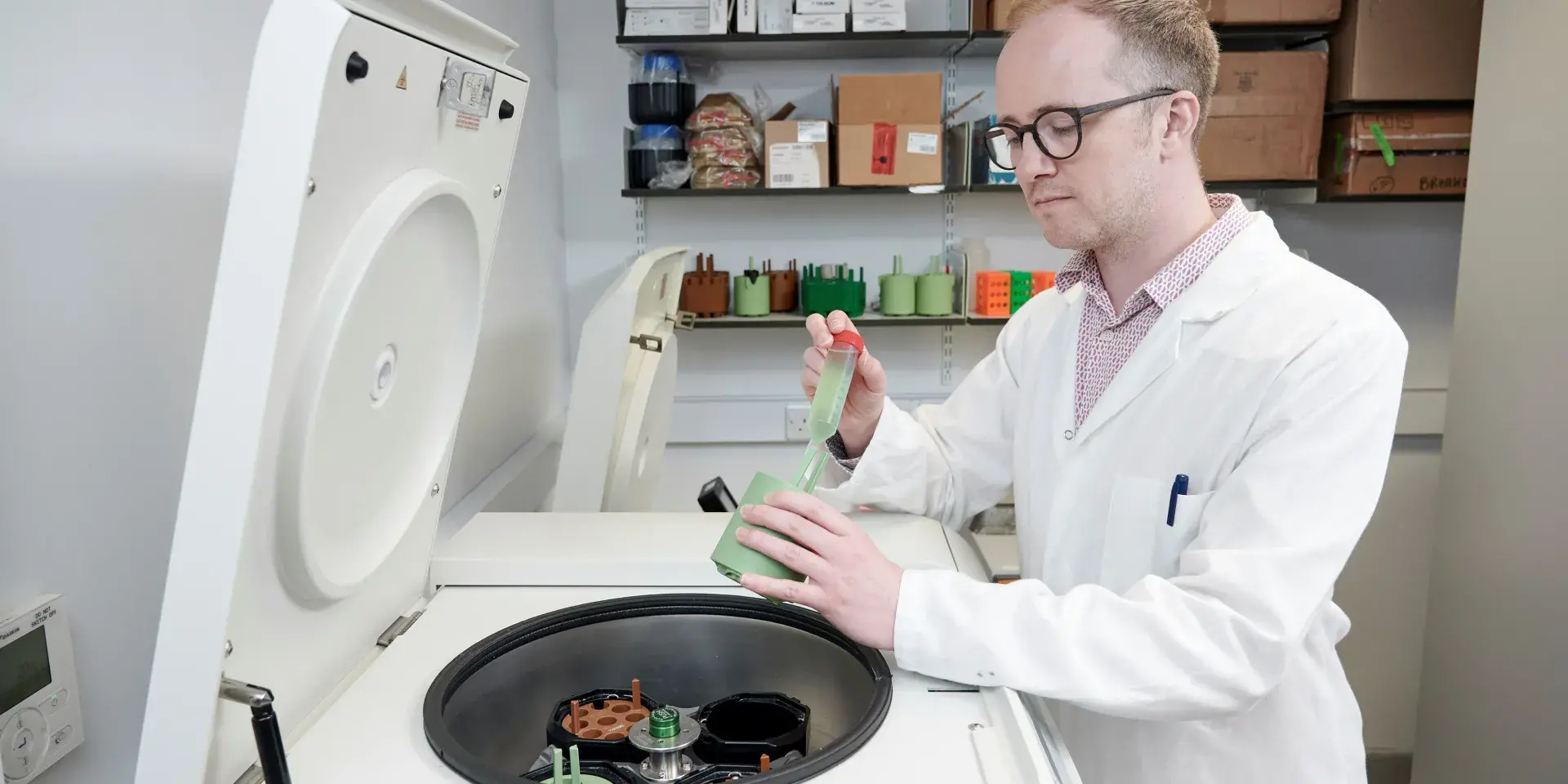 A man in a laboratory wearing a white coat transferring liquid between two containers