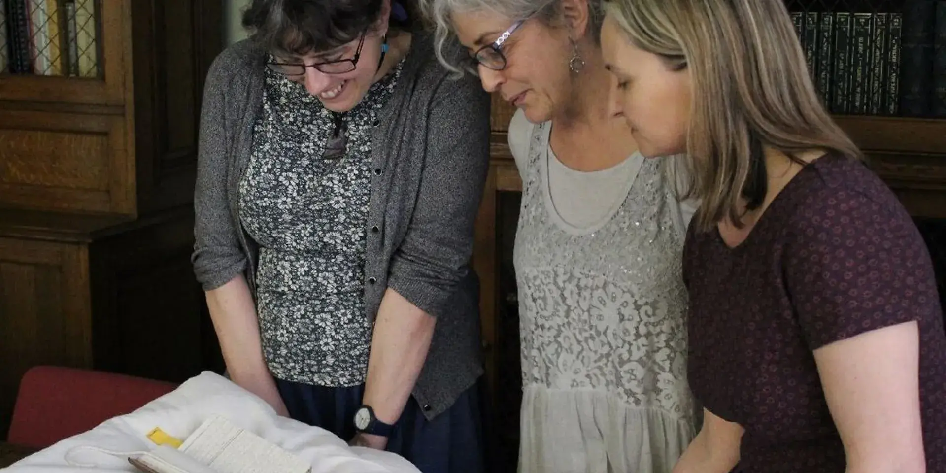 Group of three people looking at a historic book
