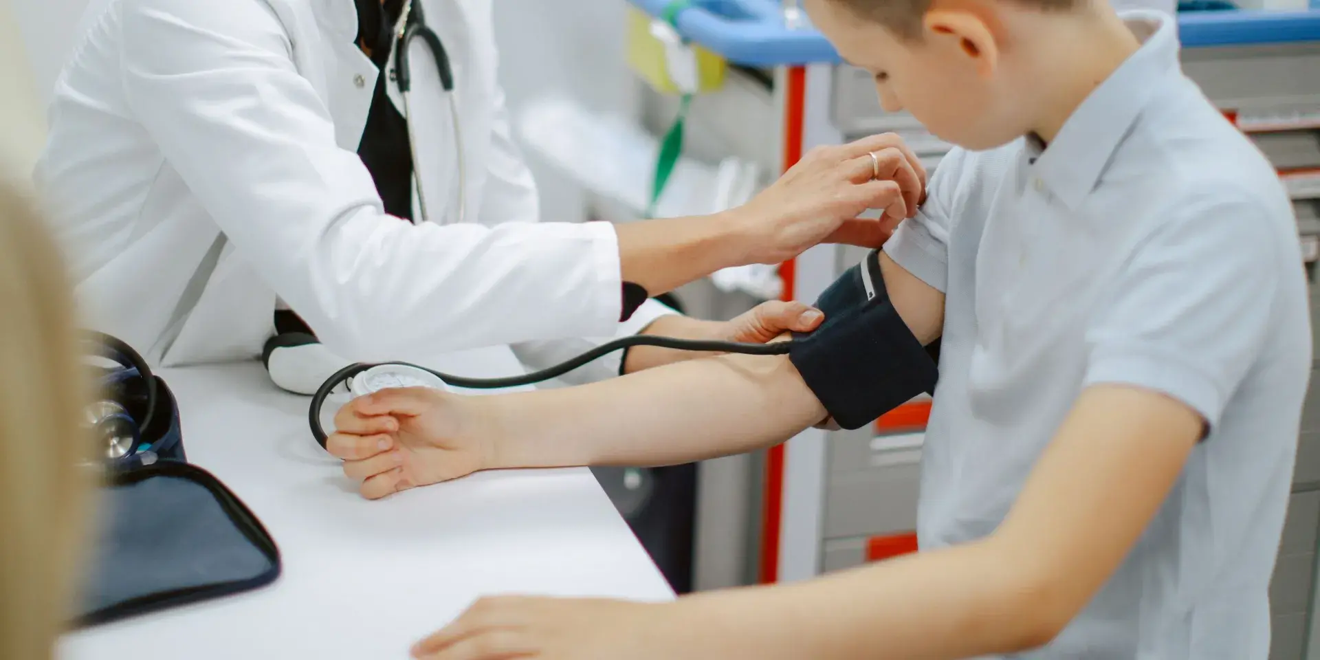 Doctor measuring blood pressure of a boy at the hospital