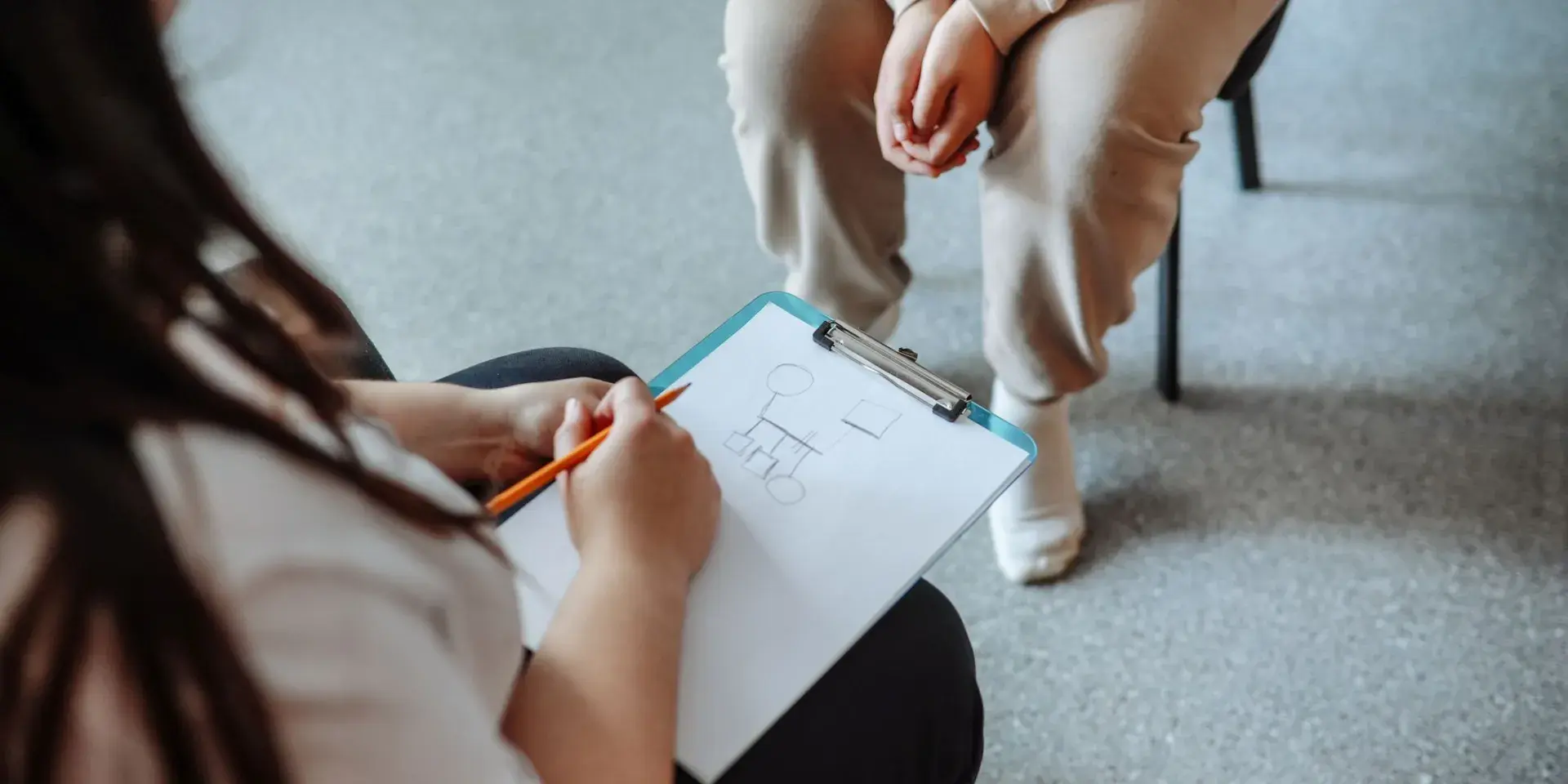 Psychologist draws on a piece of paper while counseling a teenage girl