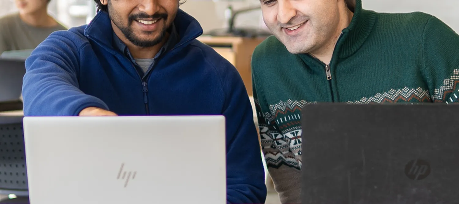 two students looking at laptops 
