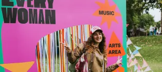 A woman wearing a cap stood in front of a banner displaying the "Everywoman" logo in pink and green.
