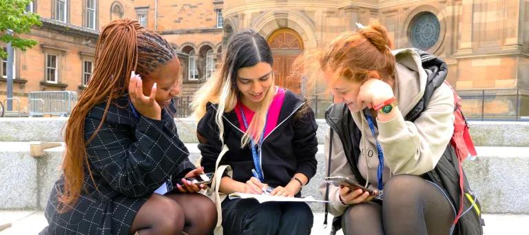 3 summer school students sitting in Bristo square