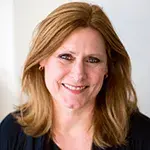 Sarah Brown smiling to camera in front of a neutral blurred background. 