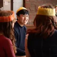 Students sit around a table wearing festive hats