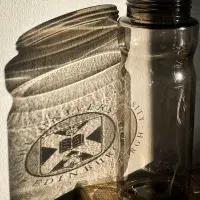 Hard light shining through a branded Uniersity of Edinburgh bottle creates a shadow with an outline of the logo on a nearby wall