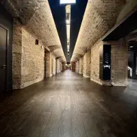 A long stone corridor with dark wooden flooring