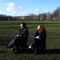 Two friends sit on fold-our chairs in The Meadows
