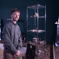 A student artist poses in front of their installation. 