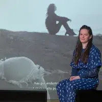 A student artist poses in front of their installation. 