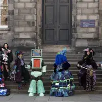 Six students pose on the steps at Old College Quad in costumes that will be on display during the 2025 Performance Costume Show