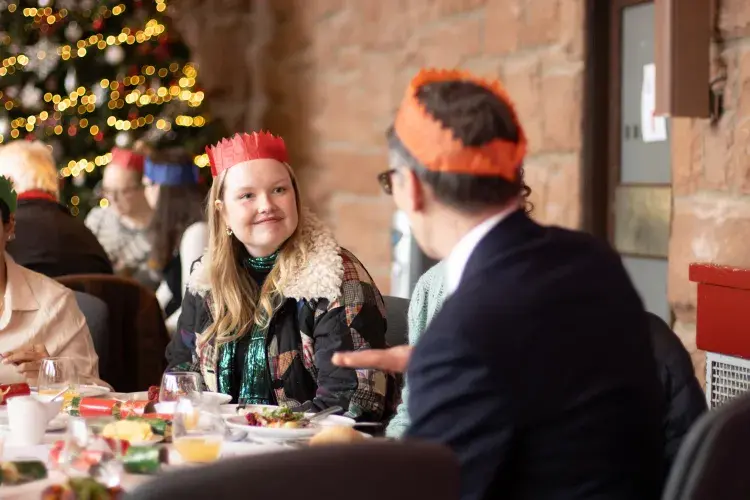A student talks to a member of staff in front of a Christmas tree
