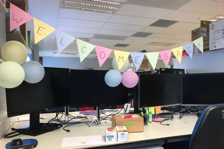 Bunting hung above an office desk displays the words 'Welcome Back'