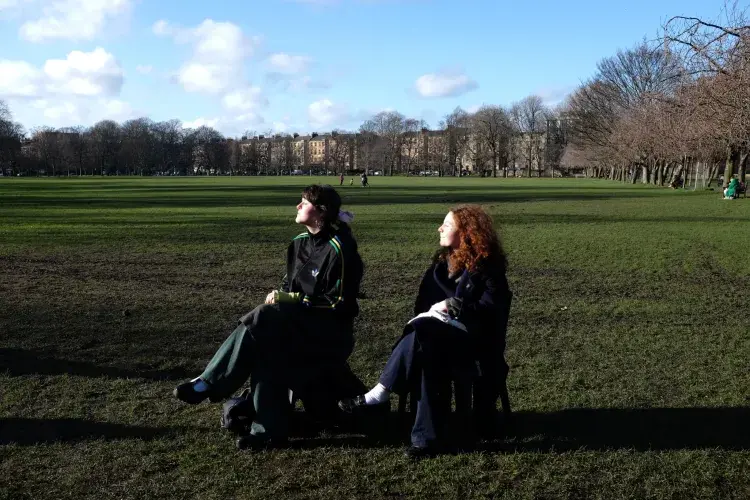 Two friends sit on fold-our chairs in The Meadows