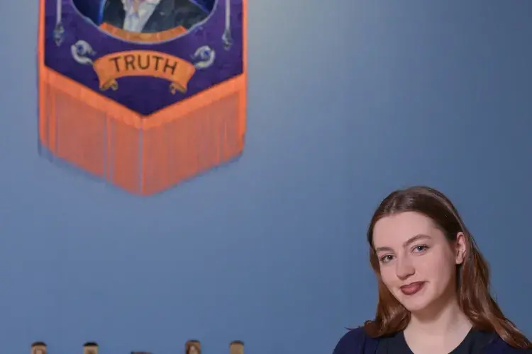 A student artist poses in front of their installation. 