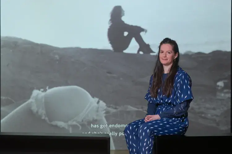 A student artist poses in front of their installation. 