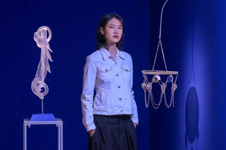 A student artist poses in front of their installation. 