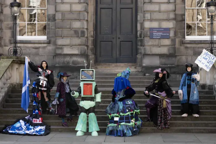 Six students pose on the steps at Old College Quad in costumes that will be on display during the 2025 Performance Costume Show