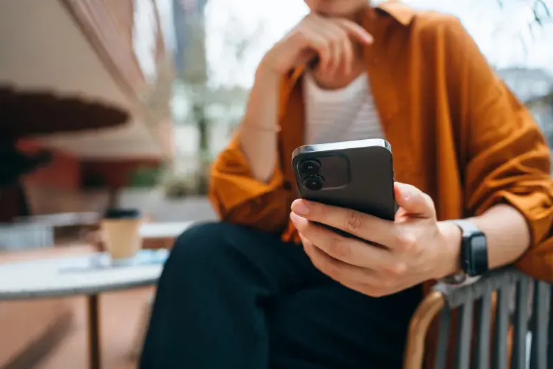 Close up shot of a person using a smartphone while sitting at a table