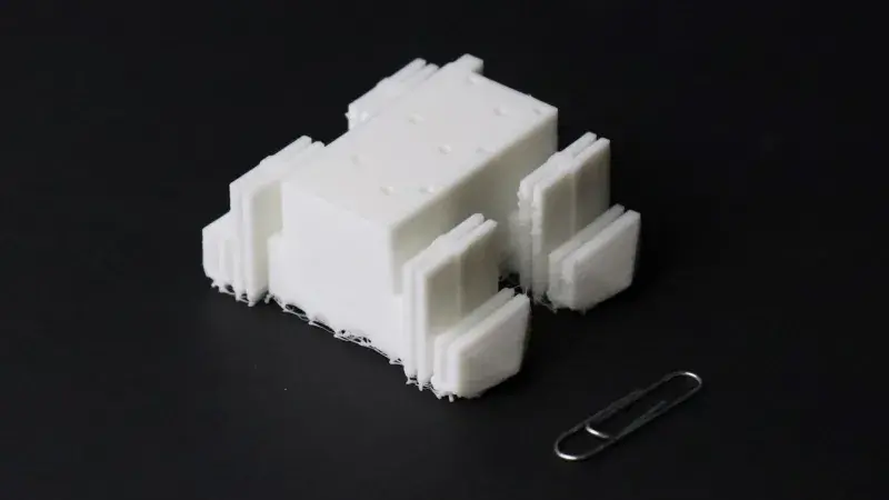 A four-legged robot made of soft plastic next to a paperclip