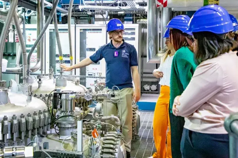 Group of people wearing hardhats being shown scientific equipmenttechnology
