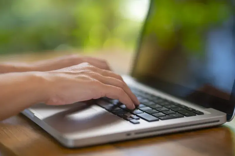 Blurred close-up image of person typing on a laptop